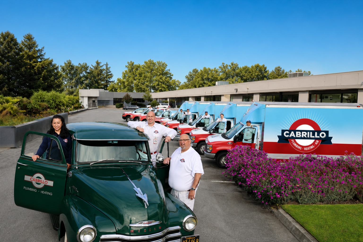 Cabrillo Plumbing, Heating & Air's red-and-white service fleet outside the San Francisco shop — uniformed technicians beside the trucks and the round-crest CABRILLO box truck anchoring the row, with landscaped purple flowers and the shop building behind.