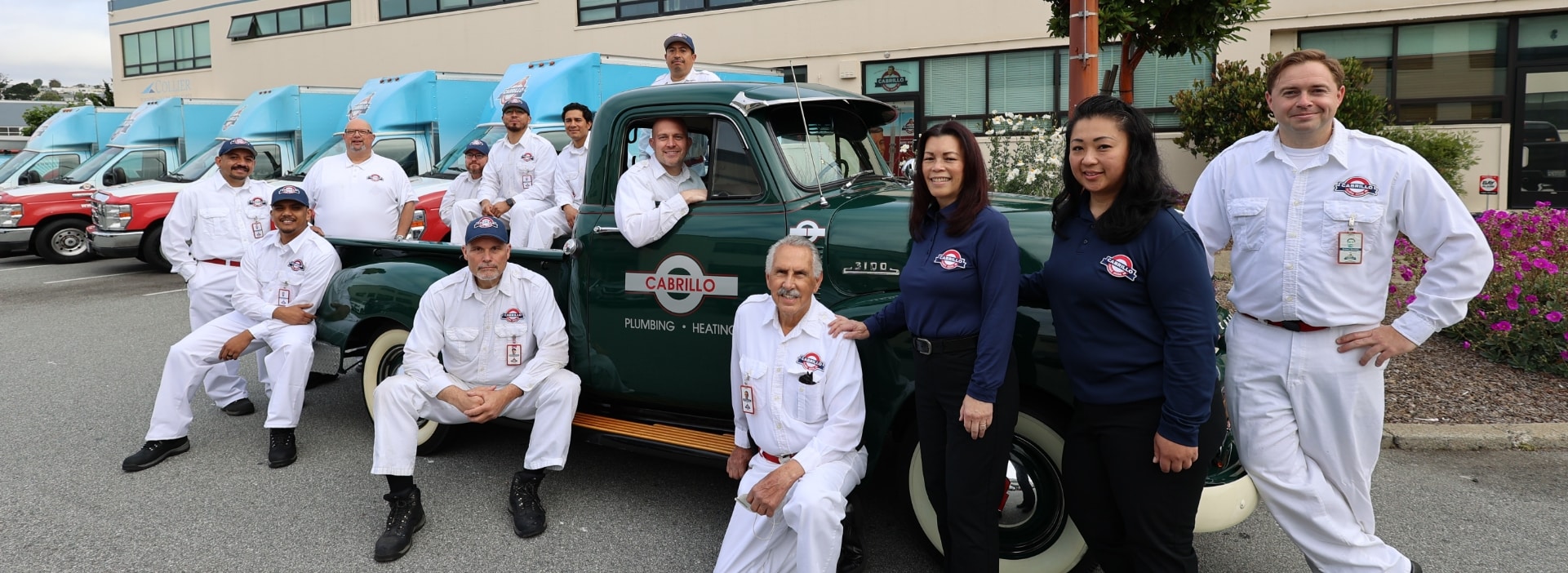 The full Cabrillo Plumbing, Heating & Air team gathered around their restored vintage green pickup outside the company's San Francisco shop.