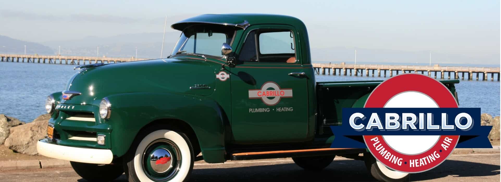 Cabrillo's restored 1950s green Chevrolet pickup parked along the San Francisco bay, reflecting the company's roots since 1961.